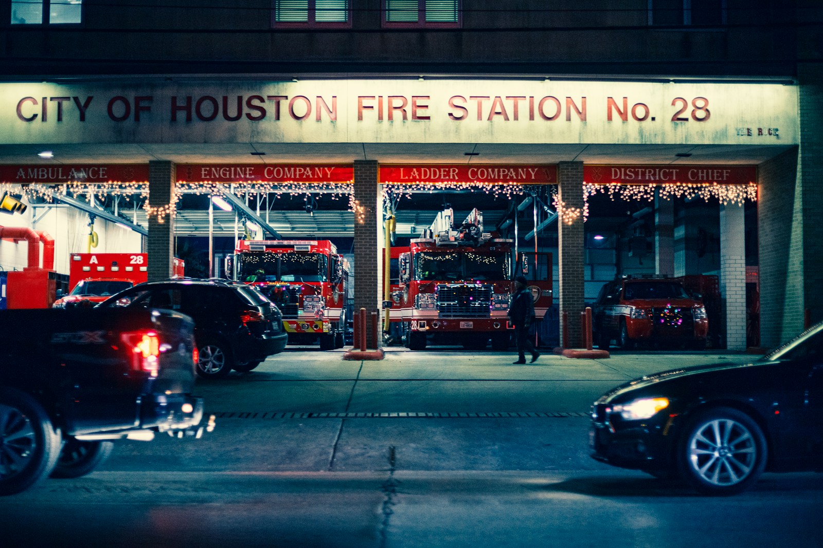 cars on road passing by City of Houston Fire Station No. 28 at nighttime